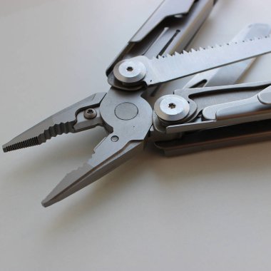 Çeşitli Bıçaklar ve Metal Saplı Profesyonel Katlama Çoklu Aracı Pense Ayrıntılı Görüntü. Tümünü Çelikten yapılmış bir alet çantasının içinde sıkıştır