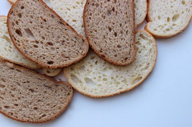 Taze pişmiş buğday ve çavdar ekmeğinin aynı dilimleri. Dilimlenmiş ekmek beyaz düz bir resimde izole edilmiş.