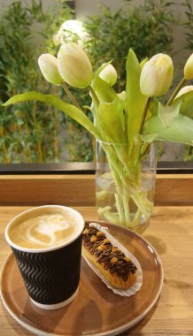 Kapuçino bardağının zarif bir sunumu üzerinde fındıkla süslenmiş vazoda çiçek açan bir vazo.