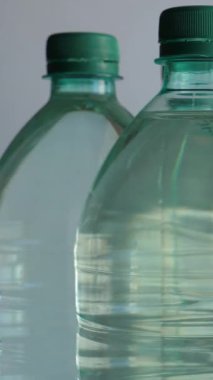 Beyaz zemin üzerinde dönen maden suyu dolu plastik şişe kapaklarının dikey videosu