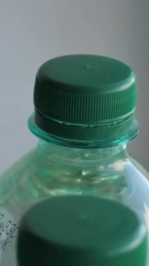 Son kullanma tarihi damgalı karbonatlı suyla dolu aynı plastik şişelerin dikey videosu konveyör üzerinde dönüyor.