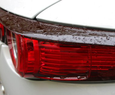 Beyaz bir arabanın plastik kapağına düşen yağmurun ayrıntılı görüntüsü