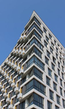  Kıvrımlı köşeli buzdağına benzeyen kentsel bir apartmanın alışılmadık mimarisi. Mavi gökyüzü arkaplanı üzerinde yerleşim binasının orijinal tasarımı
