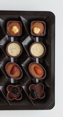 Küçük bir kutuda dört çeşit el yapımı çikolata ve tatlı arka planı için dikey stok fotoğraf.