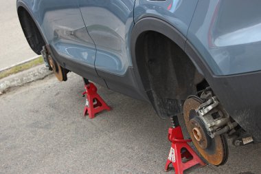 Profesyonel valelerin asfalt üzerinde kaldırılan bir arabanın tekerleklerini söktükten sonra aç