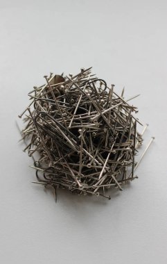 İğneler, ataçlar ve küçük tırnaklar, temiz beyaz masa dikey fotoğrafının yüzeyinde bir araya geldi. 