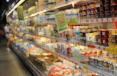 Buzdolabının önündeki bulanık fotoğrafçı ve marketteki sütle oyalanan kadın. Bir Alışverişçi, büyük bir mağazadaki Süt, Kefir, Krem ve Kır Peyniri Dükkanlarından Ürünleri Seçer