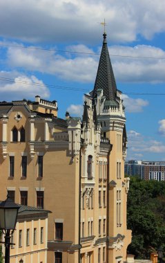 Arka planda modern şehir manzarası olan ortaçağ şatosu tarzı bir bina. Modern şehirde farklı mimari çözümlerin karışımı 
