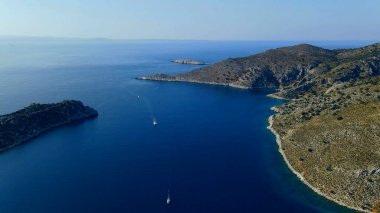 Çapalı yelkenli ve yelkenli yatı olan pitoresk bir deniz kıyısındaki korunaklı körfezin yüksek hava manzarası. 