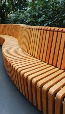 Alışveriş merkezinin yeşil alanındaki ahşap kirişlerden yapılmış dalga şeklinde bank.