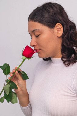 Hermosa joven olfatea rosa de perfil