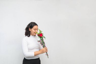 Hermosa joven mujer olfatea ramo de rosas