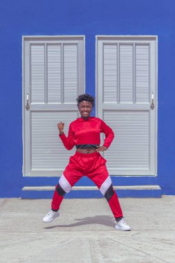 Jover mujer afro realiza baile estilo urban on parque local con save azul y puertas de fondo