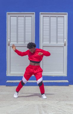 Jover mujer afro realiza baile estilo urban on parque local con save azul y puertas de fondo