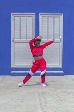 Jover mujer afro realiza baile estilo urban on parque local con save azul y puertas de fondo