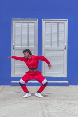 Jover mujer afro realiza baile estilo urban on parque local con save azul y puertas de fondo