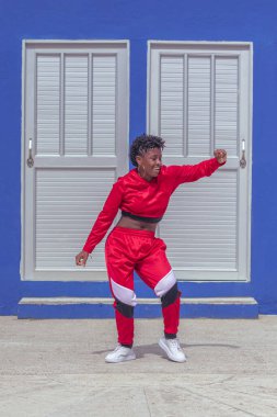 Jover mujer afro realiza baile estilo urban on parque local con save azul y puertas de fondo