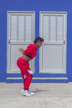 Jover mujer afro realiza baile estilo urban on parque local con save azul y puertas de fondo