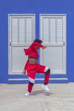Jover mujer afro realiza baile estilo urban on parque local con save azul y puertas de fondo
