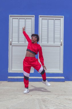 Jover mujer afro realiza baile estilo urban on parque local con save azul y puertas de fondo
