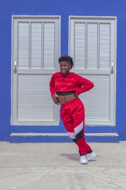 Jover mujer afro realiza baile estilo urban on parque local con save azul y puertas de fondo