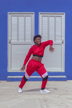 Jover mujer afro realiza baile estilo urban on parque local con save azul y puertas de fondo