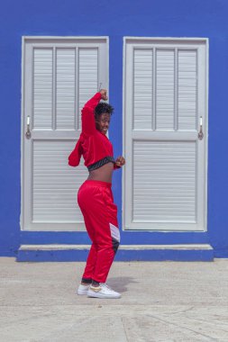 Jover mujer afro realiza baile estilo urban on parque local con save azul y puertas de fondo