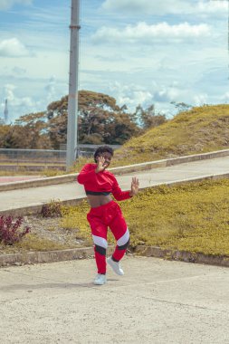 Jover mujer afro realiza baile estilo urban on parque local con hermoso y grande cielo y vejetaryen.