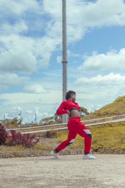 Jover mujer afro realiza baile estilo urban on parque local con hermoso y grande cielo y vejetaryen.