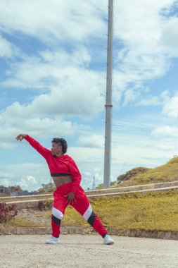 Jover mujer afro realiza baile estilo urban on parque local con hermoso y grande cielo y vejetaryen.