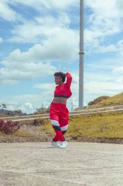 Jover mujer afro realiza baile estilo urban on parque local con hermoso y grande cielo y vejetaryen.