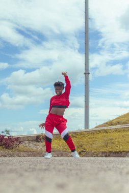 Jover mujer afro realiza baile estilo urban on parque local con hermoso y grande cielo y vejetaryen.