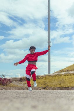 Jover mujer afro realiza baile estilo urban on parque local con hermoso y grande cielo y vejetaryen.