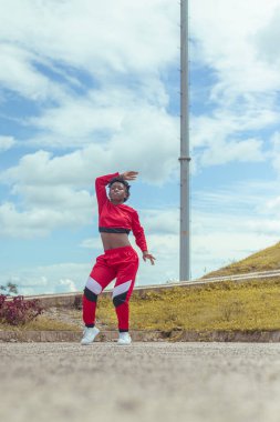 Jover mujer afro realiza baile estilo urban on parque local con hermoso y grande cielo y vejetaryen.