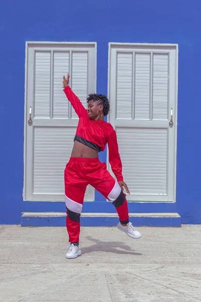 Jover mujer afro realiza baile estilo urban on parque local con save azul y puertas de fondo