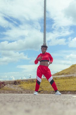 Jover mujer afro realiza baile estilo urban on parque local con hermoso y grande cielo y vejetaryen.