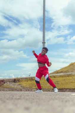 Jover mujer afro realiza baile estilo urban on parque local con hermoso y grande cielo y vejetaryen.