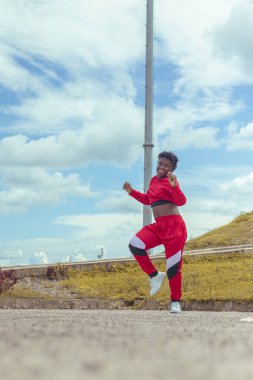 Jover mujer afro realiza baile estilo urban on parque local con hermoso y grande cielo y vejetaryen.