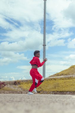 Jover mujer afro realiza baile estilo urban on parque local con hermoso y grande cielo y vejetaryen.