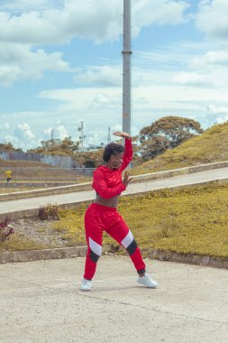 Jover mujer afro realiza baile estilo urban on parque local con hermoso y grande cielo y vejetaryen.