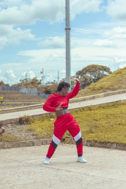 Jover mujer afro realiza baile estilo urban on parque local con hermoso y grande cielo y vejetaryen.