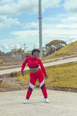 Jover mujer afro realiza baile estilo urban on parque local con hermoso y grande cielo y vejetaryen.