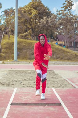 Joven afro bailando al estilo urbano en un parque, con hermosa veacion y cielo de fondo