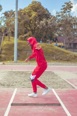 Joven afro bailando al estilo urbano en un parque, con hermosa veacion y cielo de fondo