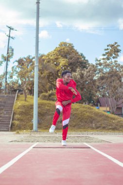 Joven afro bailando al estilo urbano en un parque, con hermosa veacion y cielo de fondo