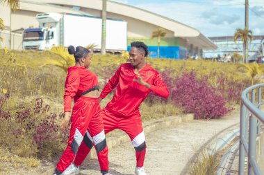 Pareja de bailarines afro realizan actuacion de baile en parque con hermosa veacion y hermoso cielo azul