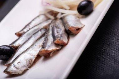 Beyaz tabakta soğanlı kızarmış ringa balığı.