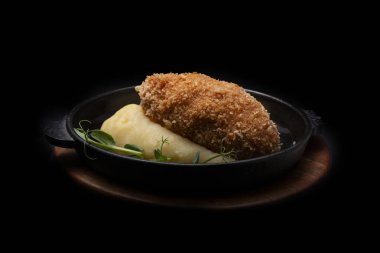 Siyah arka planda peynir ve soslu patates püresi.