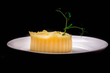 Siyah arka planda izole edilmiş siyah tabakta tereyağlı ve naneli Fransız tatlısı.