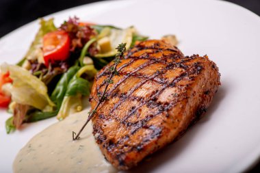 Beyaz tabakta salata ile ızgara somon bifteği.